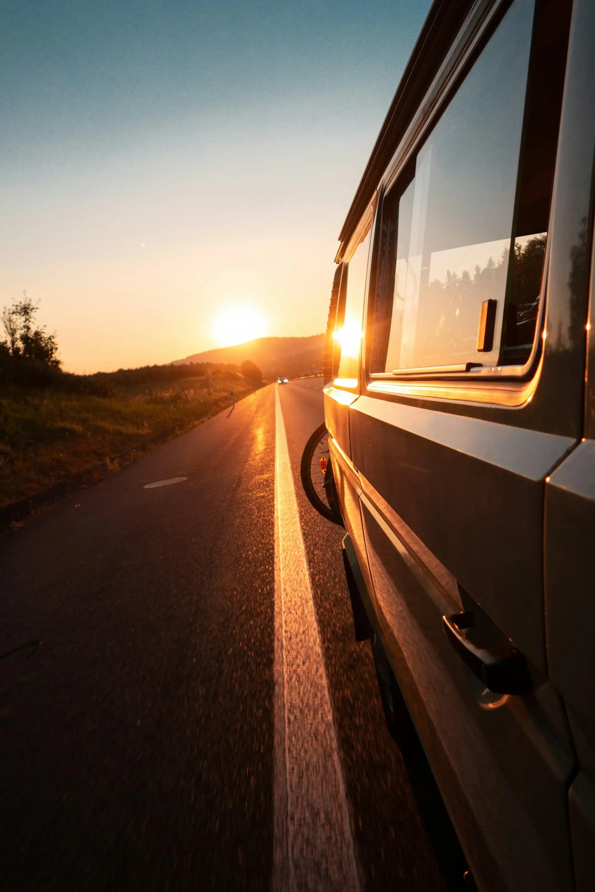 A campervan on the open road at sunset